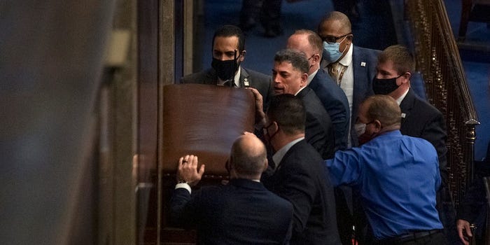 Rep. Andrew Clyde, R-Ga., second from top left, and security barricade the door of the House chamber as rioters disrupt the joint session of Congress to certify the Electoral College vote on Wednesday, January 6, 2021. Reps. Troy Nehls, R-Texas, blue shirt, Markwayne Mullin, R-Okla., right, and Dan Meuser, R-Pa., second from right, are also pictured. (Photo By Tom Williams/CQ-Roll Call, Inc via Getty Images)