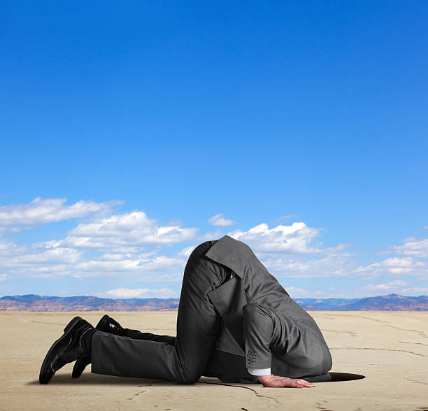businessman-burying-his-head-in-the-sand-picture-id175212000