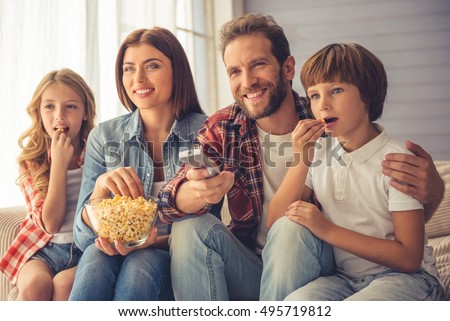 stock-photo-beautiful-young-parents-and-their-children-are-watching-tv-eating-popcorn-and-smiling-while-450w-495719812.jpg