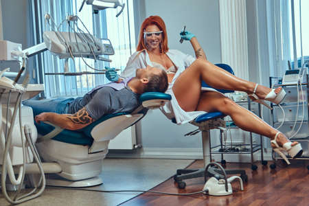 93879011-una-mujer-dentista-pelirroja-caliente-cuidando-a-su-paciente.jpg